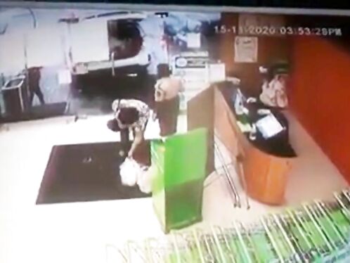 Husband Sitting In Car While Wife Putting Shopping Bags In Trunk