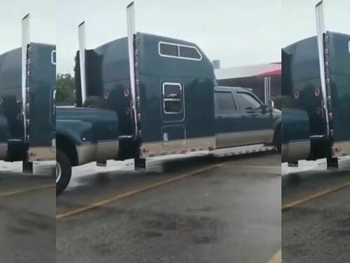 A truck drives over a pickup truck on a flatbed