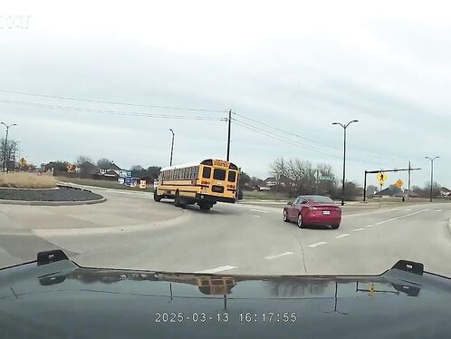 Red car nearly misses a school bus at an intersection