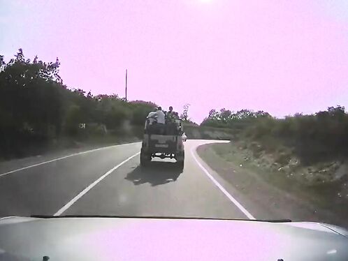 People packed on truck bed drive through winding roads