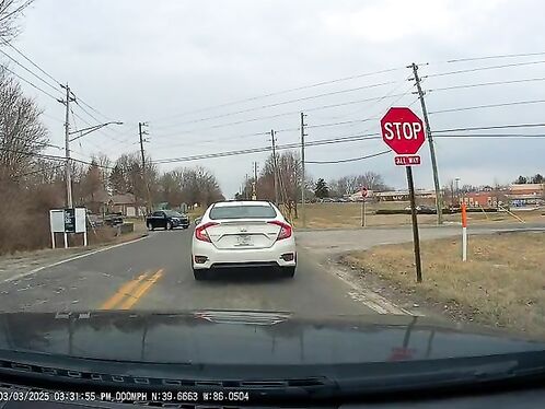 Red car blows past stop sign at intersection