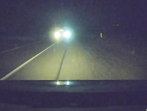 Ominous headlights flash brightly in dark, empty road