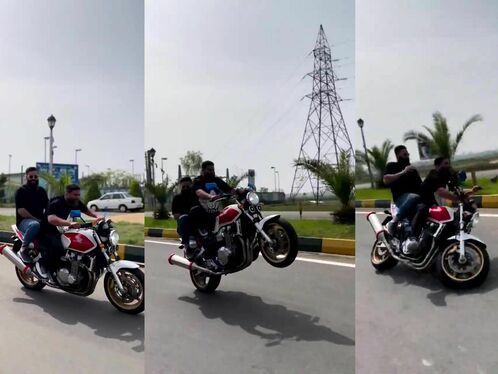 Man performs wheelie on motorcycle with passenger