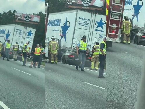 Black car rear ends semi truck on the highway