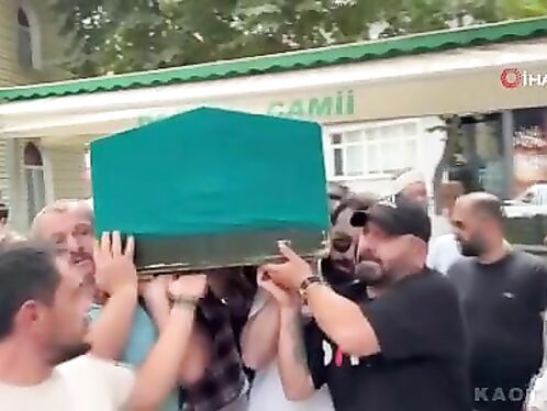 Crowd moves coffin on a busy street