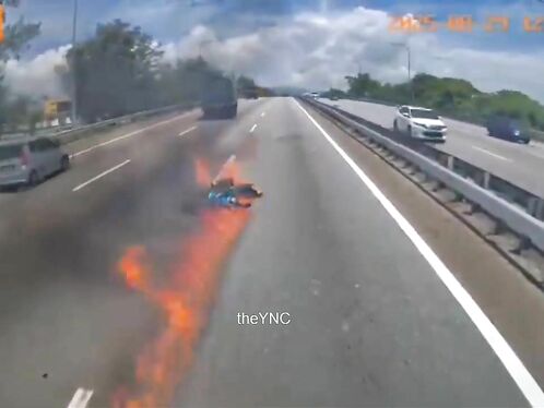 A man crashes a motorcycle and it catches fire