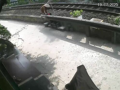 Elderly man crosses train tracks with cane