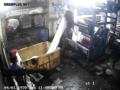 Factory workers struggle to lift heavy white bundle