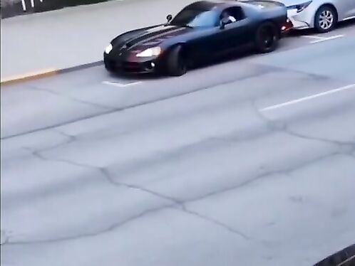 Black sports car drifts around a corner in parking lot