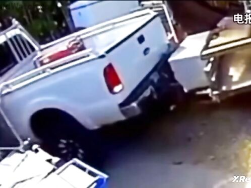 Guy pushes truck with boat trailer on grass