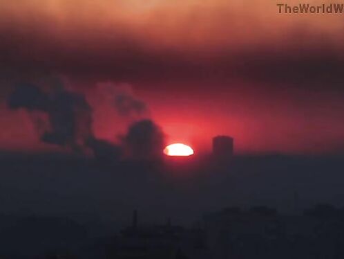 Birds fly into sunset over industrial site