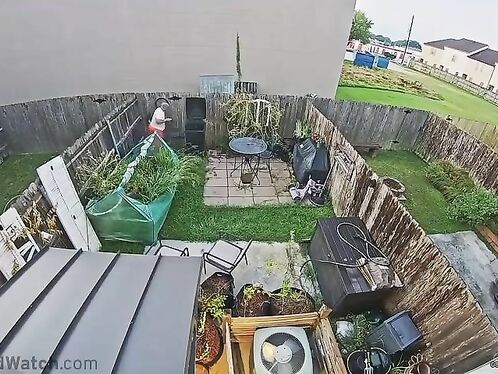 Man lifts large air conditioner in backyard