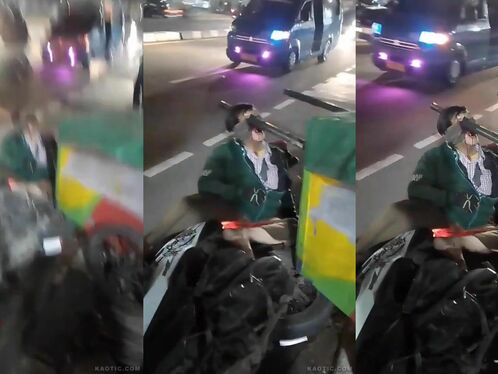 Man sits in street holding Brazilian flag as cars pass by